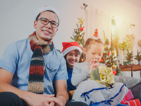 Asian young family on Christmas exchanging presents and enjoying their time together. Focus on the little girl.の写真素材