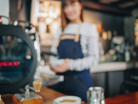 blurred background of young woman barista are preparing coffee drink behind counter.の写真素材