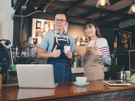 Asian man and woman barista successful small business owner standing at bar counter, Owner small business concept.の写真素材