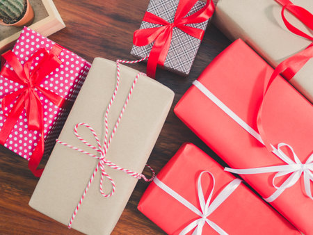 Red and brown gift box with a ribbon and bow on wooden table at home.