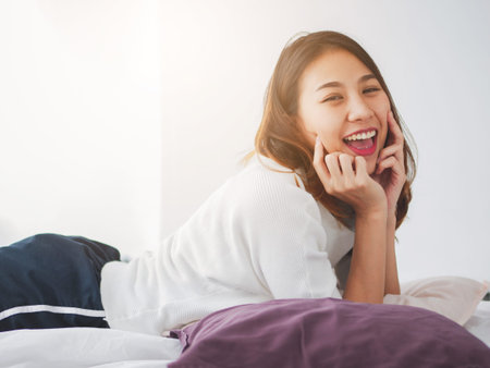 Young asian woman smiling happiness on the bed, Beautiful females looking at camera.の写真素材
