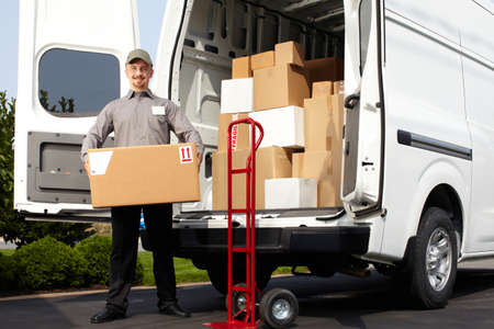 Young delivery man with parcel near cargo truck. Shipping service. Young delivery man with parcel near cargo truck. Shipping service.