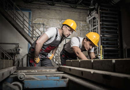 Worker and foreman in a safety hats performing quality check on a factory Worker and foreman in a safety hats performing quality check on a factory