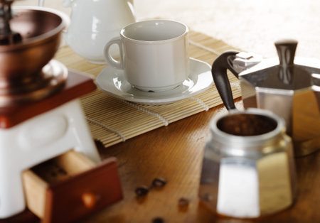 Making coffee. Coffee grinder, cup, light background