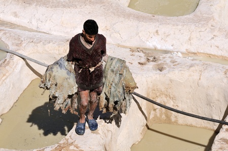 FES - MARCH 10: Unknown man works to prepare leather in a tannery in city Fes, Morocco. In Fez there are the most ancient tanneries in the world. March 10, 2012 Fes, Morocco.のeditorial素材