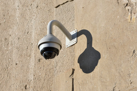 Modern CCTV security camera on stone building wall outdoors