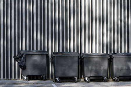 Large garbage containers, trash dumpsters standing in row at wallの写真素材