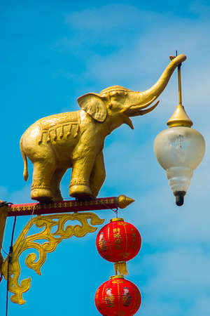 Lamp post in shape of golden elephant against blue sky, Thailand.の写真素材