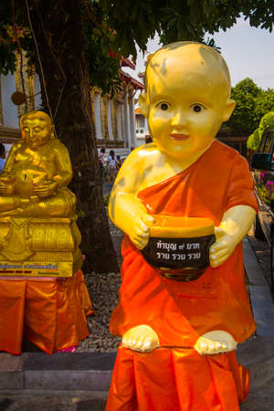 Sculpture of a boy with a Cup at the temple..The Temple of Dawn Wat Arun and a beautiful blue sky in Bangkok, Thailandの写真素材