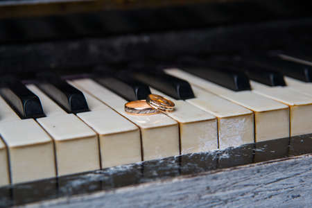 Two beautiful wedding rings lie on black and white keys of the pianoの写真素材