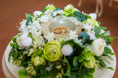 Two beautiful gold wedding rings for the couple lie on a saucer with flowers.の写真素材