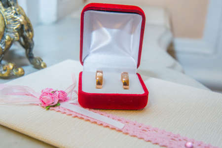 Two beautiful wedding gold rings with diamonds are in a red box.の写真素材