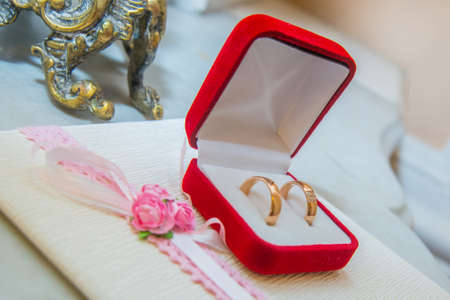 Two beautiful wedding gold rings with diamonds are in a red box.の写真素材