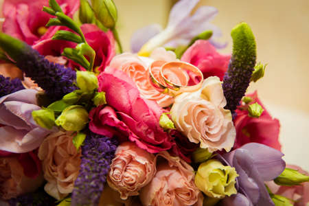 Two beautiful gold wedding rings lie on a bouquet.の写真素材