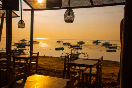 Beautiful beach with a cafe in Sanur with local traditional boats. Indonesia.Dawn on the island of Bali.の写真素材