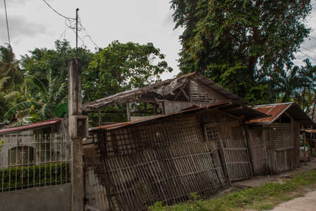 Normal local old wooden house and huge green trees in cloudy weatherの写真素材