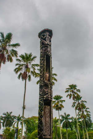 Ancient Totem pole against the sky and palm trees. Kuching. Sarawak. Borneo. Malaysia.の写真素材