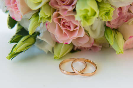Gold wedding rings and flowers. Brides bouquet of pink rosesの写真素材