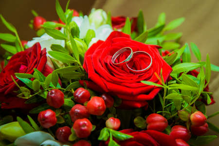 Two gold wedding rings lying on a red roseの写真素材