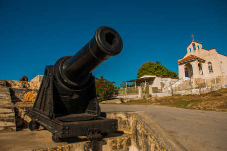 Gun at the entrance to the fortress and the Catholic Church. Fortress Fortaleza de Jagua. Old fortress South of Cienfuegos in Cuba.の写真素材