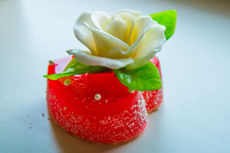 White rose with green leaves on a red marmalade heart. Delicious sweets for lovers and weddings.の写真素材