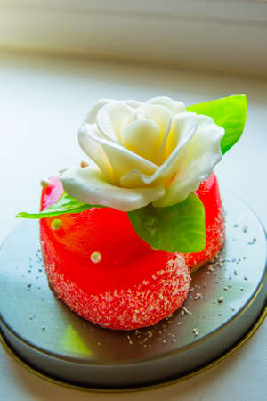 White rose with green leaves on a red marmalade heart. Delicious sweets for lovers and weddings.の写真素材