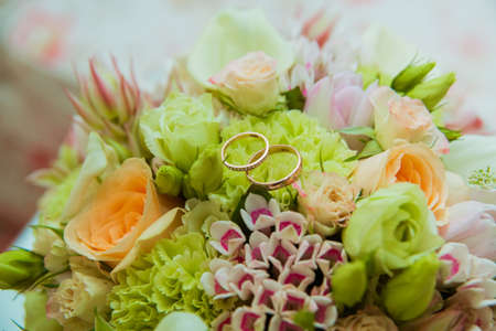 Wedding ring. Two gold rings with diamonds bride and groom and a bouquet of delicate flowers.の写真素材