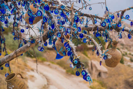 blue bead worn against the evil eye as talisman hanged on tree in cappadocia on a sunny day. Cappadocia, Uchisar, Turkey.の写真素材