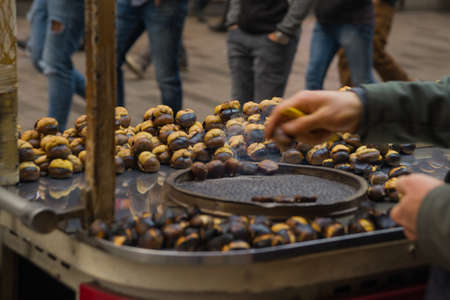 Hands of street vendor chestnuts. Roasted chestnuts in street vendors. Popular food among tourists and Turks. Istanbul, Turkey.の写真素材