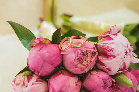 Beautiful delicate wedding bouquet of pink peonies and wedding rings of the bride and groom. Wedding day.の写真素材