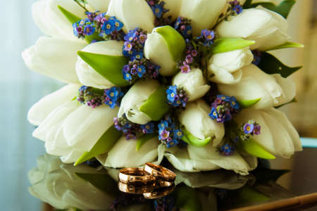 Wedding rings of the bride and groom on a Beautiful wedding bouquet of white tulips. Wedding day.の写真素材