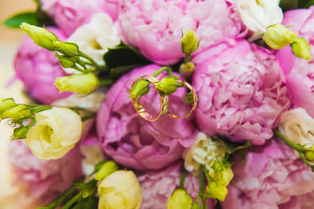 Beautiful delicate wedding bouquet of pink peonies and wedding rings of the bride and groom. Wedding day.の写真素材