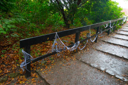 White spider Web and lantern on wooden bridge in autumn forest on Halloween holiday. Denmark, Europe