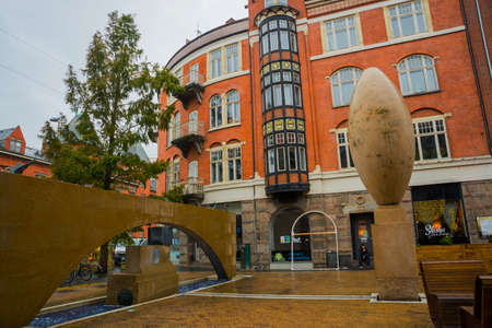 Odense, Denmark: A beautiful street with buildings, a fountain and an unusual monument in the form of an egg. Odense, Denmark. Europeの写真素材