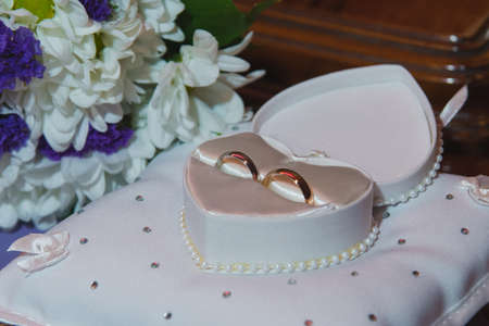 Beautiful wedding rings in a box in the form of a heart and a bouquet of white chrysanthemums....