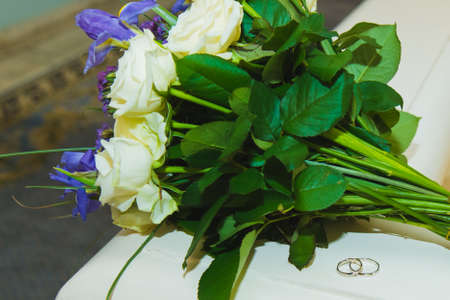 Beautiful delicate wedding bouquet white roses and wedding rings of the bride and groom. Wedding day.の写真素材