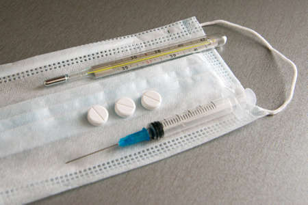 The mask, medical syringe, thermometer and tablets are on the table. Tools needed for the virus.