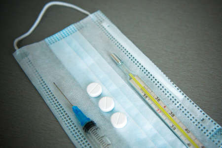 The mask, medical syringe, thermometer and tablets are on the table. Tools needed for the virus.