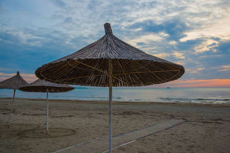 DURRES, ALBANIA: Palm beach umbrellas against the background of the evening sky on the beach, Durres, Albania.の写真素材