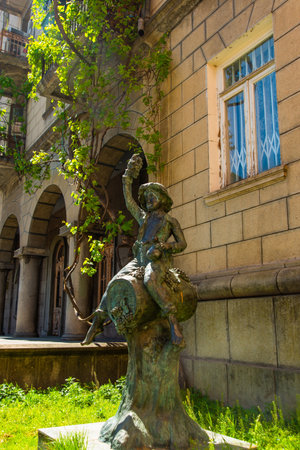 BATUMI, GEORGIA: The famous Sculpture of a boy sitting on a wine barrel located in the center of Batumi. Unusual bronze statues of Georgia dedicated to winemaking.のeditorial素材