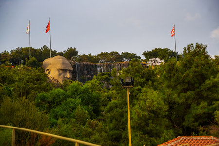 ANTALYA, TURKEY: Statue of Mustafa Kemal Ataturk and an artificial waterfall, at the entrance to the city forest, an observation deck, a large stone head and trees on a rock.のeditorial素材