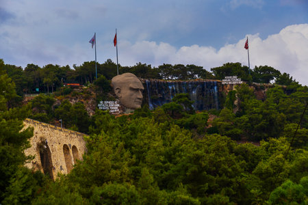 ANTALYA, TURKEY: Statue of Mustafa Kemal Ataturk and an artificial waterfall, at the entrance to the city forest, an observation deck, a large stone head and trees on a rock.のeditorial素材
