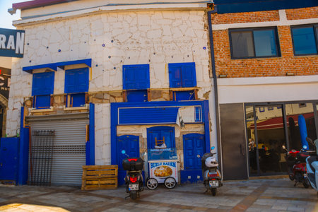BODRUM, MUGLA, TURKEY: A traditional street with white walls and blue windows in Bodrum on a sunny day. Typical Mediterranean village scene in whitewashed walls by lush greenery.のeditorial素材