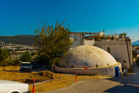 BODRUM, MUGLA, TURKEY: A traditional street with white walls and blue windows in Bodrum on a sunny day. Typical Mediterranean village scene in whitewashed walls by lush greenery.のeditorial素材