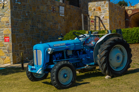 DATCA, MUGLA, TURKEY: Blue tractor near a stone building on a sunny day.