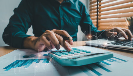 Businessman analyzing investment charts with calculator and laptop. Accounting and financial concept.の素材
