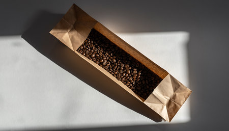 Brown paper bag filled with coffee beans on white surface.の素材
