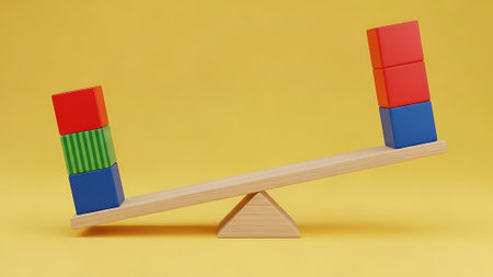 A seesaw with blocks of different colors stacked on each end, balanced on a yellow surface.の素材