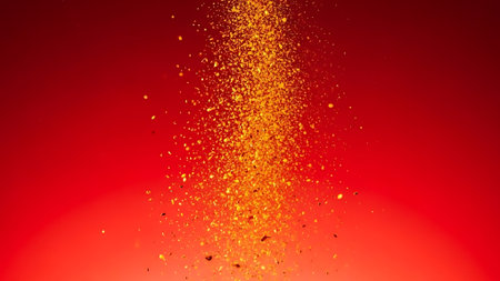 Glittering gold particles burst upwards on a red background.の素材