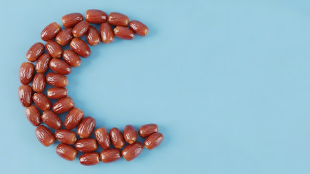 Ramadhan islamic themed still life with dates arranged as a crescent moon on blueの素材